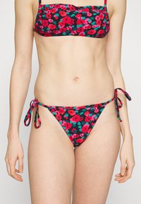 Conjunto de biquíni com fundo preto, apresentando um padrão floral em rosa, vermelho e verde-água. O top tem alças finas; a parte de baixo tem cordões nas laterais.