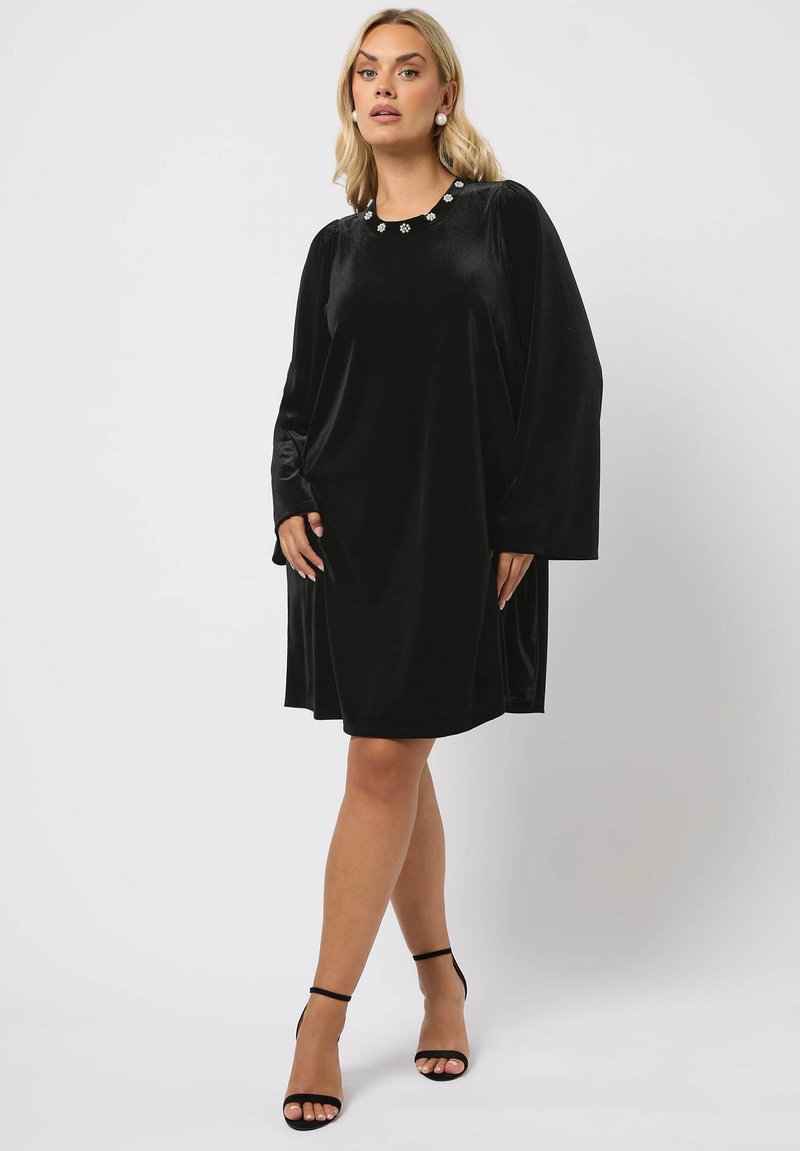 Schwarzes Samtkleid mit rundem Halsausschnitt, geschmückt mit dekorativen Verzierungen. Verfügt über lange Ärmel und eine lockere, fließende Silhouette.
