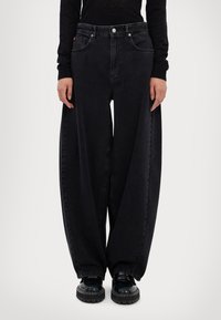 Mustat denim-housut, joissa on leveä ja rento istuvuus. Ominaisuuksiin kuuluvat viisi taskua, vyölenkit ja nappikiinnitys. Rakenteellinen kangas, jossa on pieni kiilto.