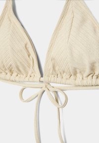 Haut de bikini triangle beige côtelé avec fines bretelles réglables à nouer et un subtil éclat dans la texture du tissu.