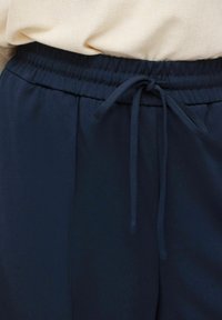 Marineblå joggebukser med elastisk midjebånd og snor. Glatt stoff, sidelommer og avslappet passform for komfort.