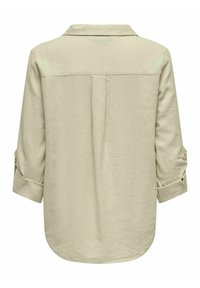 Lys beige langærmet skjorte med nedfoldet krave, opkrøllede ærmer, rygfælde detaljer og rundet kant. Lavet af et blødt, struktureret stof.