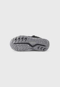 Sole of black and gray outdoor shoe with deep treads, zigzag patterns, and a "KEEN" logo in the center.