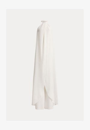 Bijela haljina bez rukava s halter-izrezom, nabrane izrezom i visokim nižim preklopom koji se proteže iznad širokih hlača.