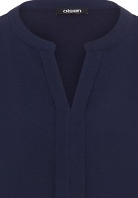 Blusa blu navy con scollatura rotonda e mezza apertura, realizzata in tessuto testurizzato con finitura liscia. Etichetta del marchio "olsen" visibile sul colletto.