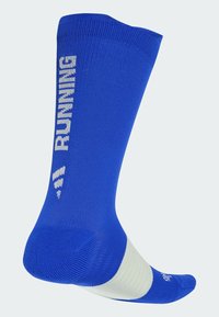 Blauwe sport sok met een witte band bij de enkel, met "RUNNING" verticaal in het wit gedrukt. Gemaakt van ademend breimateriaal.