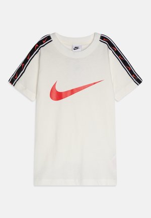 Valkoinen Nike-pikeepaita, jossa on lyhyet hihat, edessä suuri punainen Swoosh-logo ja mustat hartiaraitoja, joissa useita pieniä punaisia Swoosh-logoja.