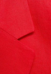 Tissu rouge texturé avec deux pièces superposées, présentant une finition lisse et un tissage légèrement rugueux, renforçant sa profondeur et son intérêt visuel.