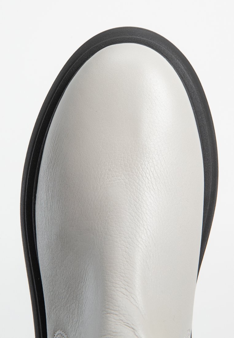 Scarpa in pelle grigio chiaro con una superficie liscia, punta arrotondata, suola in gomma nera e dettagli in cucitura. Design minimalista, profilo elegante.