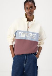 Fehér, kék és bordó színű, színblokkolt pulóver zippzáros gallérral, amelyen a "CONVERSE ALL-STAR" felirat található az elülső részen. Pamut keverék.
