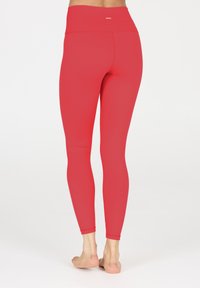 Rode legging met een hoge tailleband, gemaakt van rekbaar materiaal. Naadloos ontwerp, aansluitende silhouet en enkel lengte. Platlock stiksels.