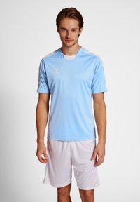 Ljusblå fotbollsrinning med kort ärm och V-hals, vita detaljer på axlarna och en logotyp på bröstet. Matchas med vita shorts.