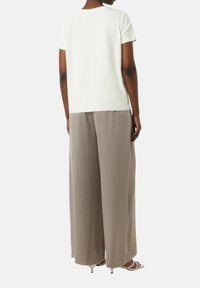 Relaxed-fit white t-shirt paired with light grey wide-leg trousers, featuring smooth fabric and a minimalist design.