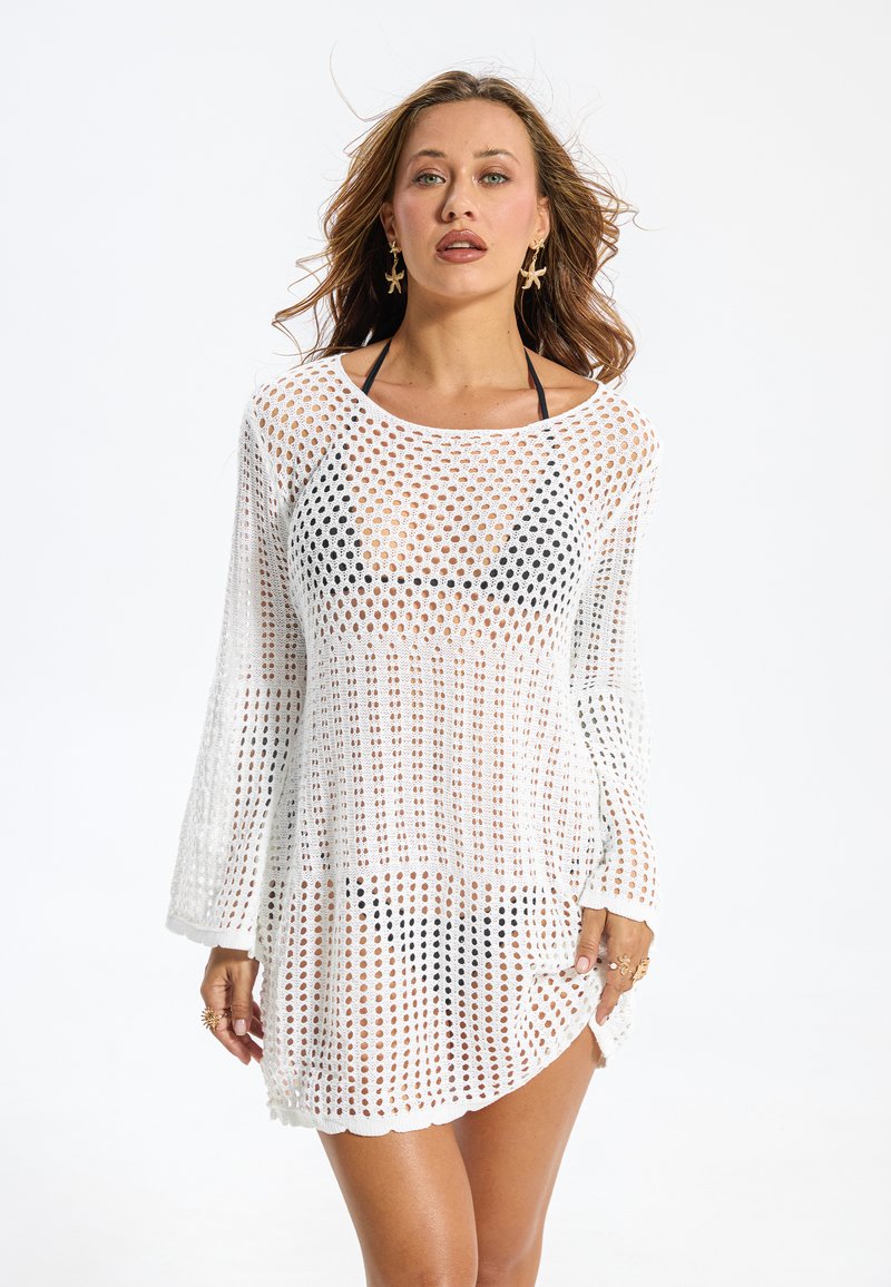 Robe de couverture blanche en crochet à manches longues, présentant un motif à mailles larges et ouvertes avec un ourlet festonné. Convient pour la plage.