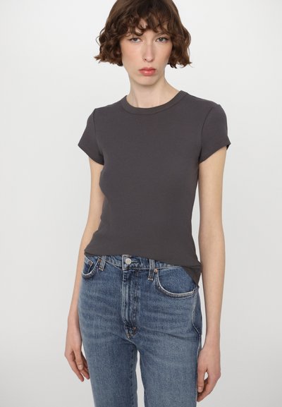 Grå ribbad t-shirt med korta ärmar och rundad urringning, parat med högmidjade blå jeans med knappstängning och fickor.