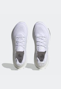 Witte sneakers met een gebreide bovenkant en een gestructureerd ontwerp. Voorzien van veters, een logo en de tekst "End Plastic Waste" aan de binnenkant. Zachte rubberen zool.
