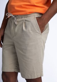 Beige shorts met een elastische tailleband en een trekkoord. Zijzakken, vervaardigd uit een lichtgewicht stof, met een relaxed fit en een zachte textuur.