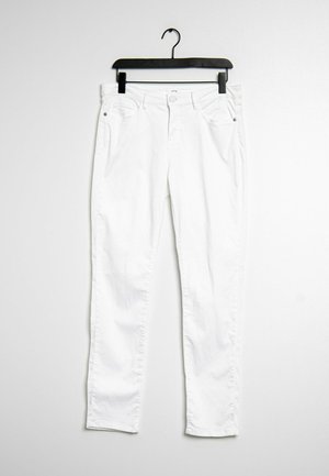 Witte slim-fit jeans hangen aan een zwarte hanger tegen een egale witte achtergrond.