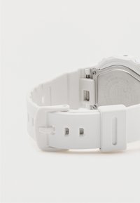 Balta derva laikrodis su tekstūruotu dirželiu, sidabrinės metalinės detalės ir graviruota nugarėlė, turintis paprastą sagtį ir išpjovimus reguliavimui.