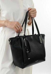 Zwarte leren tote bag met een gestructureerde afwerking, ritssluiting en lange, platte handvatten; beschikt over een zilveren hardware accent en een franjer detail.