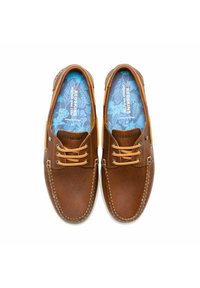 Chaussures en cuir marron avec des lacets beige, des coutures blanches et une semelle intérieure à motif bleu. Présentent une finition lisse et un design décontracté.