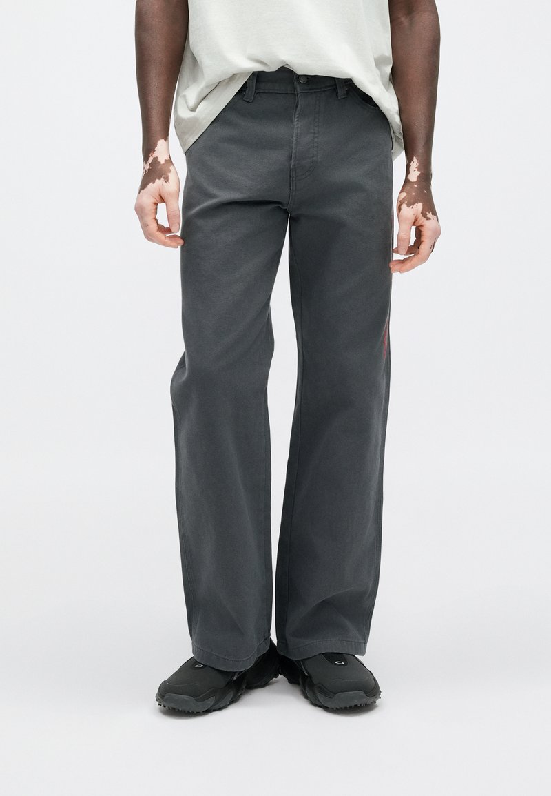 Gray wide-leg pants made of soft, durable fabric, featuring a straight cut and minimal design; paired with black footwear.
