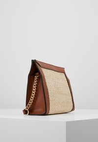Leather and straw bag with a structured shape, featuring a brown base, woven straw panel, and a gold chain strap.