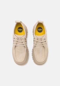 Chaussures en cuir beige avec une finition texturée, à bout rond et semelles intérieures jaunes. Elles présentent des lacets marron et un onglet arrière renforcé.