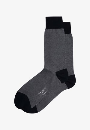 Zwarte sokken met een gestructureerd grijs stippenpatroon, geribbelde boorden en verstevigde teen- en hielgebieden voor duurzaamheid.