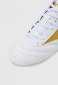 White leather soccer shoe with gold accent, featuring textured stitching, flat laces, and a rounded toe design.