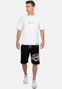 Witte katoenen t-shirt met een zwart logo, gecombineerd met zwarte shorts met een gedetailleerde rood-witte grafische print en een koord in de taille.