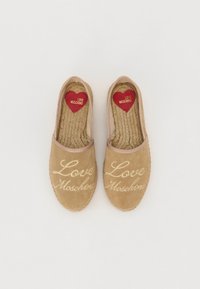 Smėlio spalvos suede espadrilės su auksine siuvinėta "Love Moschino". Apvalus pirštas, elastinės briaunos ir raudonas širdies formos padas. Lygus pintas padas.