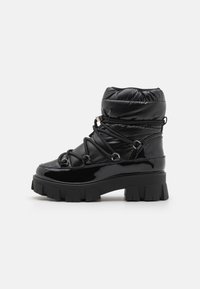 Black padded ankle boot with a glossy finish, thick rubber sole, and adjustable laces, featuring metal accents and a rounded toe.
