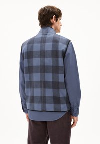 Herren Weste in Blau mit Karomuster und grauen Akzenten; aus einem Wollmischgewebe gefertigt. Verfügt über einen hohen Kragen und eine glatte untere Hemd-Schicht in einfarbig Blau.