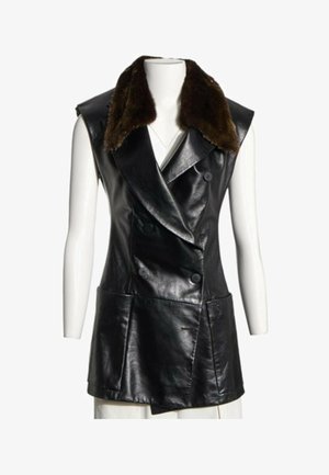 Chaleco de cuero negro sin mangas con botones cruzados y gran cuello de piel marrón oscuro sobre un maniquí blanco.