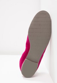 Sålen af pink ruskinds fladsko med grå gummibund præget med "Kennel & Schmenger" logo mønster.