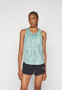 Ermeløs mintgrønn tank topp med tie-dye mønstre, rund hals, og Asics-logo på brystet, parret med svarte treningsshorts.
