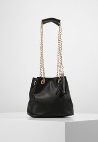 Borsa a secchiello in finta pelle nera con catene dorate, manico superiore e dettagli con frange. Presenta occhielli metallici per la chiusura con coulisse.