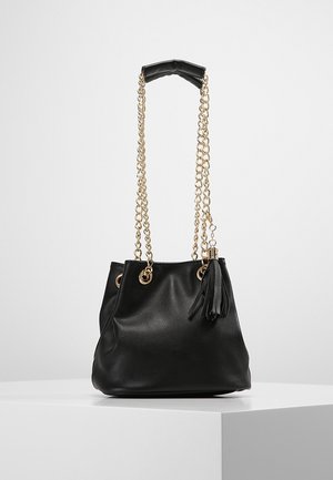 Sac seau en simili cuir noir avec des sangles en chaîne dorée, une poignée supérieure et des détails en frange. Doté d'œillets en métal pour un cordon de fermeture.