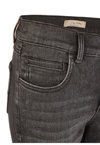 Jeans de mezclilla negra con una textura suave, que presentan costuras en contraste, un bolsillo pequeño y una etiqueta de marca en la cinturilla.