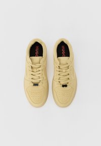Sneaker in suede giallo con accenti neri, punta perforata e branding "HUGO" su una soletta nera. Lacci piatti e suola in gomma.
