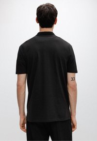 Czarna koszulka polo z krótkim rękawem, z ribbowanym kołnierzykiem i gładkim, jedwabistym materiałem. Posiada prosty dół i minimalistyczny design.