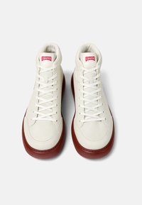 Białe skórzane sneakersy high-top z gładką cholewką i czerwoną gumową podeszwą. Cechy to kontrastowa metka z logo oraz płaskie sznurowadła.