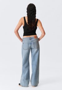 Ljusblå, vida jeans med en klassisk femfickdesign, med en strukturerad look och en brunt läderpatch på baksidan av midjan.