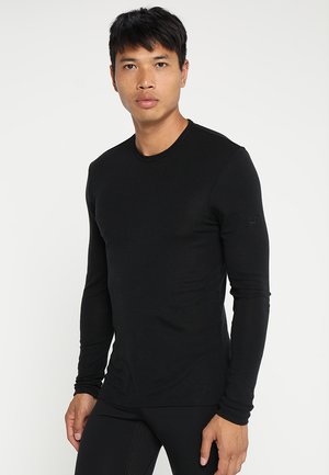 Schwarzes Langarmshirt aus leichtem Stoff, mit Rundhalsausschnitt und tailliertem Schnitt, versehen mit einem kleinen Logodetail am Ärmel.