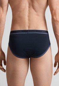 Granatowe męskie slipy z miękkim elastycznym paskiem w talii, gładkiego materiału i dopasowanym kroju. Charakteryzują się minimalnym szyciem i ścisłym dopasowaniem.