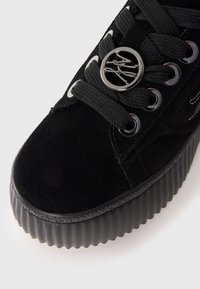 Baskets compensées en suède noir avec des lacets ronds noirs, des œillets métalliques et une semelle en caoutchouc texturée avec un design nervuré.