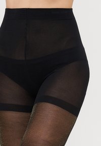 Leggings negre transparente cu talie înaltă, caracterizând o textură netedă cu accente strălucitoare în zona inferioră a piciorului, subliniind un design ajustat.