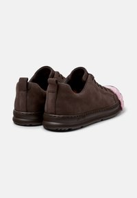 Brązowe zamszowe sneakersy z różowym gumowym noskiem, charakteryzujące się zaokrąglonym kształtem i gładkimi podeszwami. Prosty design z minimalnymi akcentami z metalowych elementów.