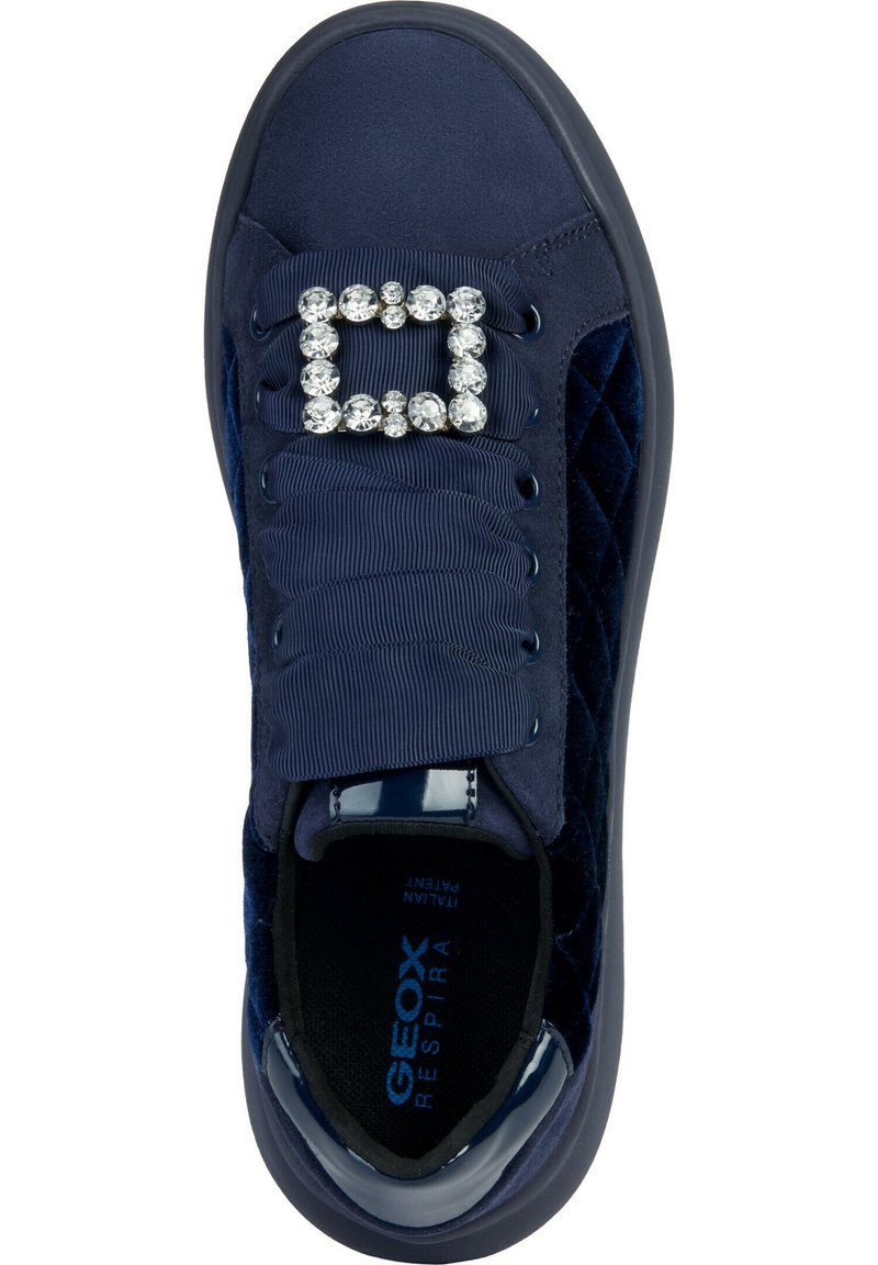 Sneaker da donna blu navy con lati trapuntati, lacci larghi e texturizzati, e una fibbia decorativa rettangolare in strass sulla parte superiore.